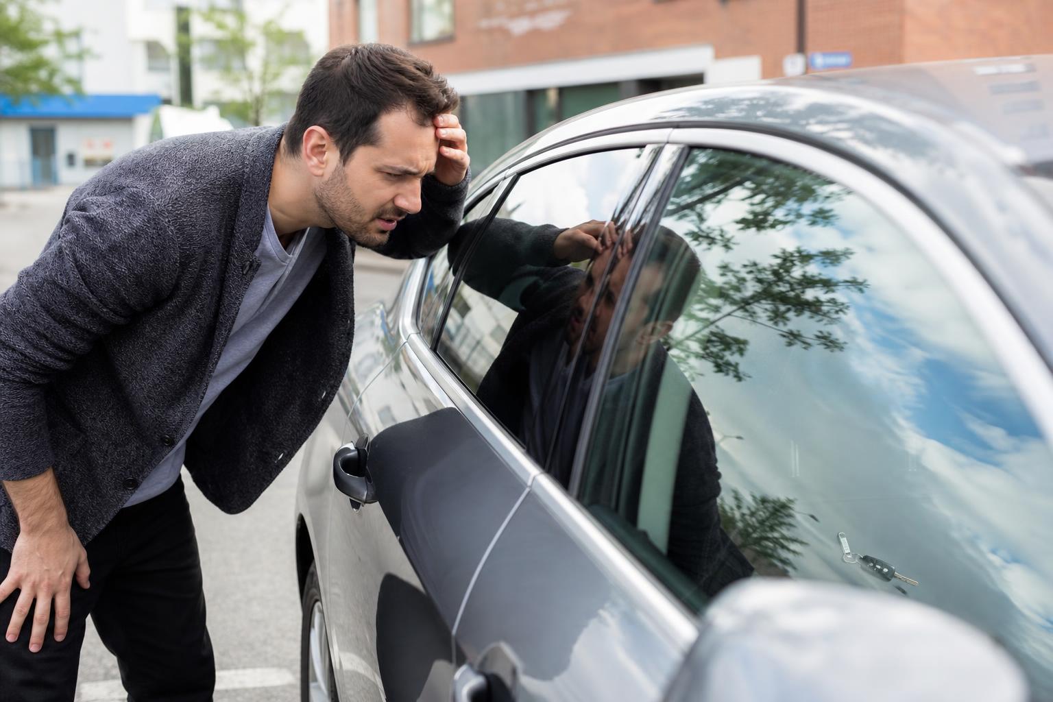 Automotive locksmith technician unlocking a modern car beside the open door